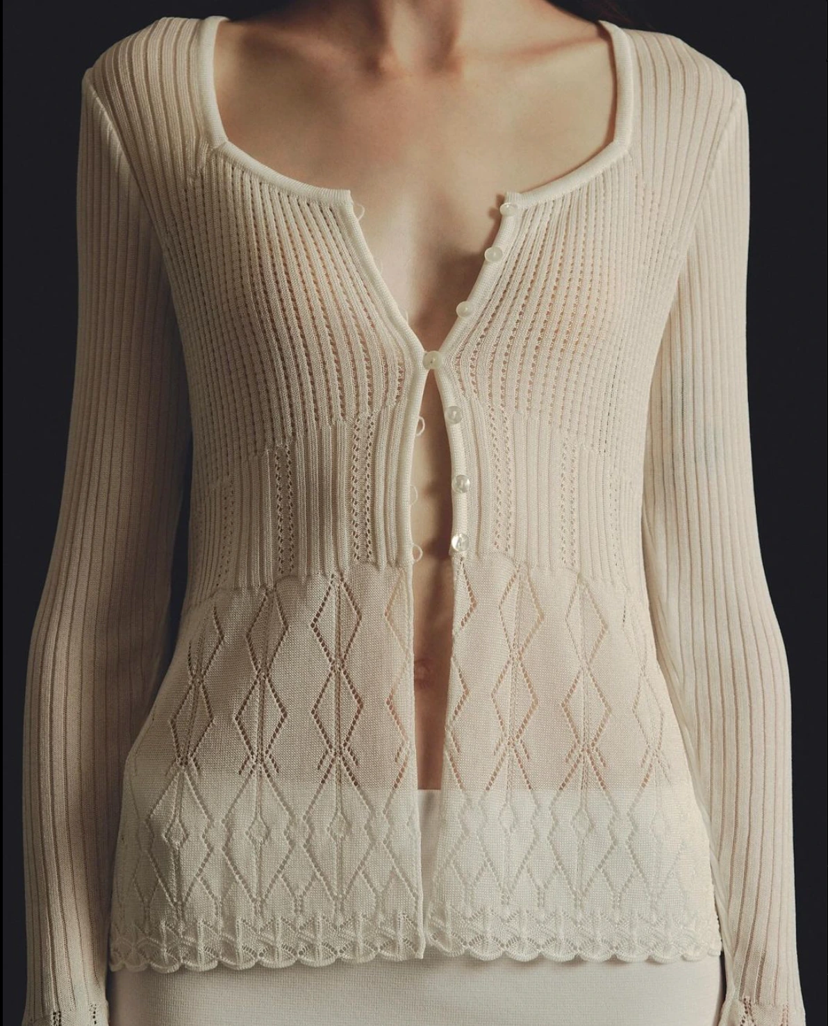 Emily Oda new campaign with A person wearing a light-colored, ribbed, and knitted cardigan with buttons, over a similar-toned top.